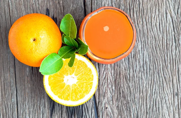 Orange juice and oranges  on a wooden floor. — Stock Photo, Image