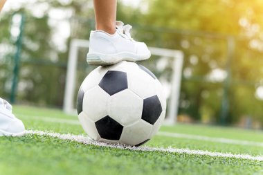 Bir futbol topu adım beyaz spor ayakkabı giyen bir çocuk metrelik.