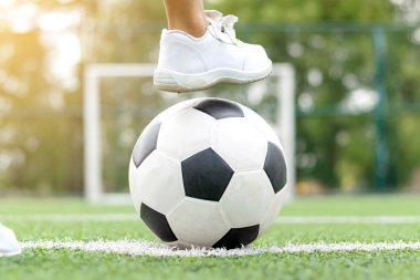 Bir futbol topu adım beyaz spor ayakkabı giyen bir çocuk metrelik.