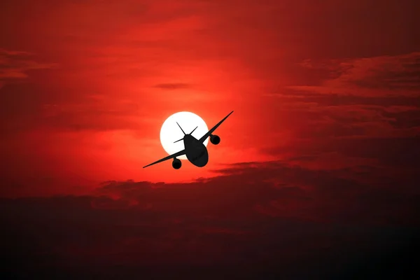 Silueta del avión en el hermoso sol y el cielo rojo . — Foto de Stock