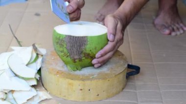 İçindeki suyu içmek için hindistan cevizini bıçakla soy..