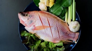 Seramik tabaklardaki taze balık ve sebzelerin en üst görüntüsü 360 derece dönerek pişirmeye hazır..