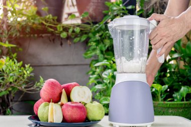 İnsanlar taze elma ve guava suyu yapmak için elektrikli blender kullanıyorlar..