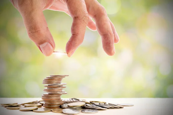 Human hand placing a coin on a pile of coins, use for for business and financial growth concepts.