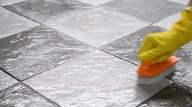 Sarı lastik eldiven takan eller yerleri temizlemek için plastik zemin temizleyicisi kullanıyor..