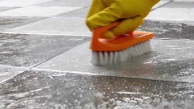 Sarı lastik eldiven takan eller yerleri temizlemek için plastik zemin temizleyicisi kullanıyor..