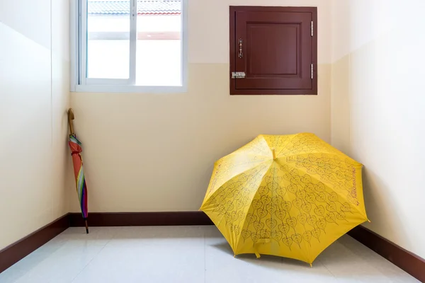 Kleurrijke paraplu's geplaatst in een hoek van de kamer. — Stockfoto