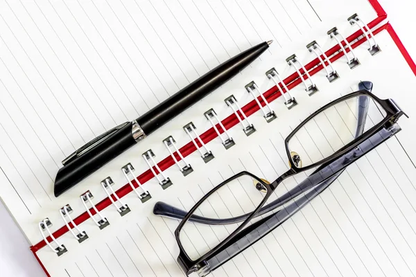 Caneta e óculos em um caderno . — Fotografia de Stock
