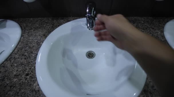 Un homme s'approche du robinet ouvre le robinet, l'eau commence à couler, se lave les mains — Video