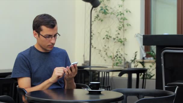 Člověk sedí u stolu v kavárně a používá telefon