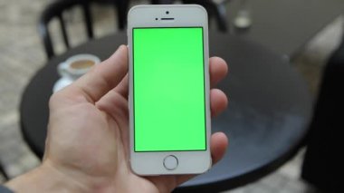 Telefon Held el ile akıllı. Yeşil ekran Chroma anahtar hareket izleme dikey. Telefon el kuvvetli darbe aşağı-yukarı animasyon üzerinde oturan kişi