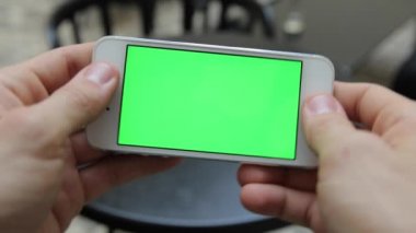 Telefon Held el ile akıllı. Yeşil ekran Chroma anahtar hareket izleme dikey. Telefon eller döndürme animasyon üzerinde oturan kişi