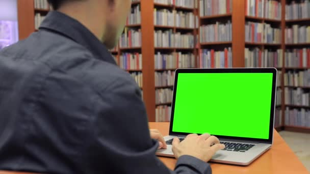 Giovane bello uomo si siede e lavora su schermo verde — Video Stock