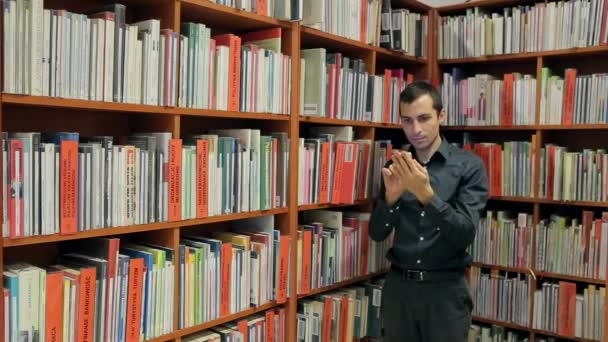 Человек, читающий книгу в библиотеке по телефону Стоковое Видео
