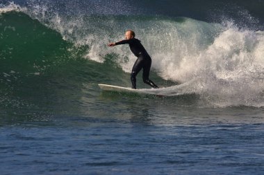 Leo Carrillo Eyalet Plajı 'nda büyük yaz dalgalarında sörf.