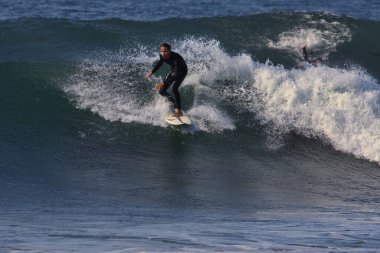 Leo Carrillo Eyalet Plajı 'nda büyük yaz dalgalarında sörf.