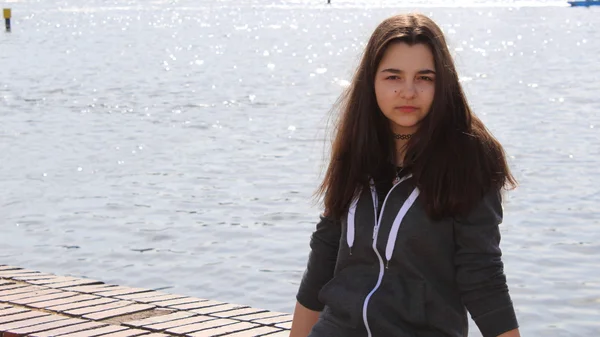 Beautiful teen girl sitting by the water — Stock Photo, Image