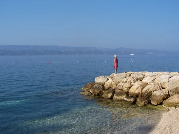 Маленькая девочка стоит на скалах на хорватском пляже — стоковое фото