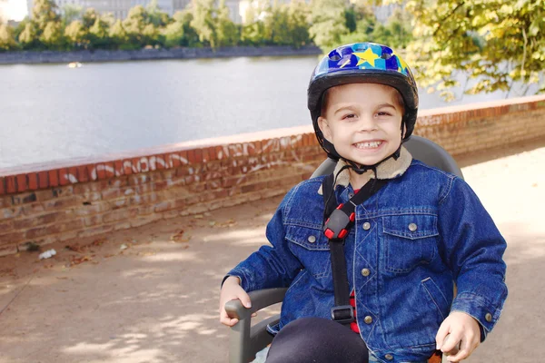 Bir bisiklet koltukta oturan bir kask ile küçük çocuk