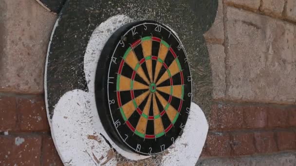 Side angle view of darts being thrown at a dart board with focus on the board — Stock Video