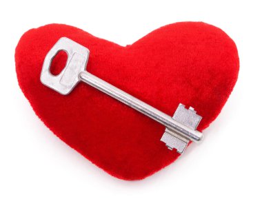 Anahtar beyaz bir arkaplanda izole edilmiş bir kalbin üzerinde yatıyor..