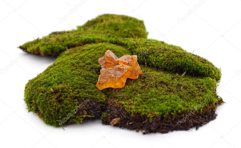 Rosin stone on green moss isolated on a white background.