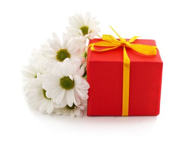 Beyaz arka planda izole edilmiş bir buket beyaz papatya krizanteminin yanında sarı bir kurdeleyle bağlanmış parlak kırmızı bir hediye kutusu..
