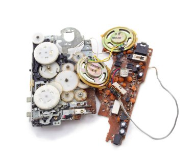 Beyaz arka planda izole edilmiş bozuk bir retro ses cihazından mekanik dişlilerin, hoparlörlerin ve elektronik devre kartının ayrıntılı görüntüsü.