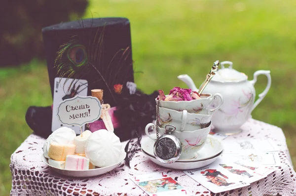 Hat, hatter, pen, tea party, Alice in Wonderland, Through the Looking-Glass, fairy tale, fantasy, scenery, eat me, drink me, candy, bubble, liquid, magic potion, table, tablecloth, lace, saucer, tea, tea, cup, dried roses, spoons, lens — Stock Photo, Image