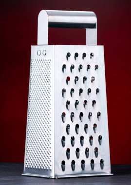 Koyu kırmızı arka planı olan peynir rendesi. Bu fotoğraf Londra, Ontario 'da bir stüdyoda çekildi.  