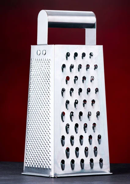 Cheese grater with a dark red background. This photo was taken in a studio in London, Ontario