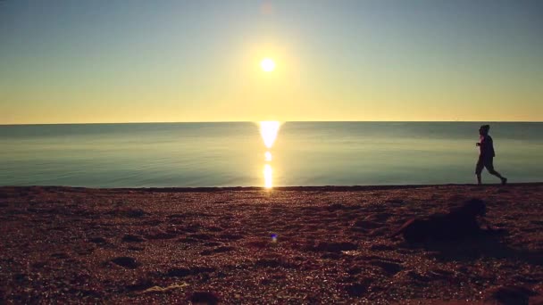 Silhouette des sportlichen aktiven Mannes beim Laufen und Trainieren am Strand bei Sonnenuntergang. — Stockvideo