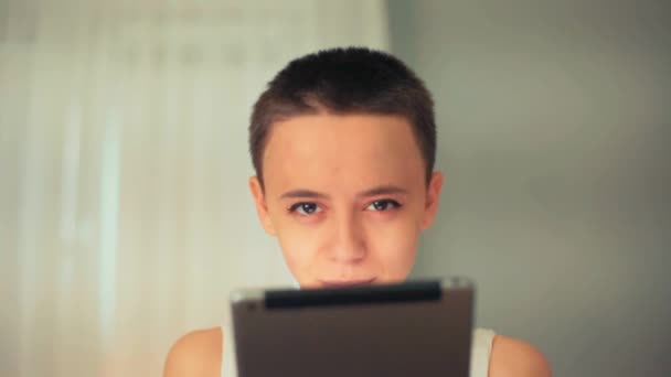 Menina careca bonita, uma menina com cabelo curto morena, está usando Tablet — Vídeo de Stock