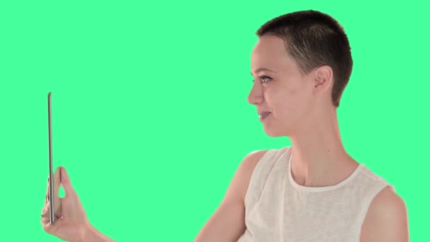 Beautiful bald girl, a girl with short hair brunette on the green screen, taking selfie with digital tablet — Stock Video