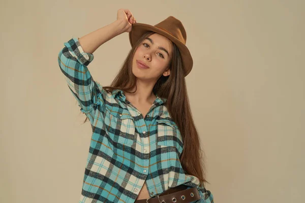 Girl in plaid shirt and cowboy hat on pink background Stock Image