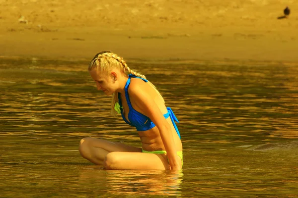 Das Mädchen im blauen Badeanzug sitzt im Wasser — Stockfoto