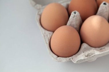 Hafif bir arka planda pakette çiğ yumurta. Güneş kabukta parlıyor.