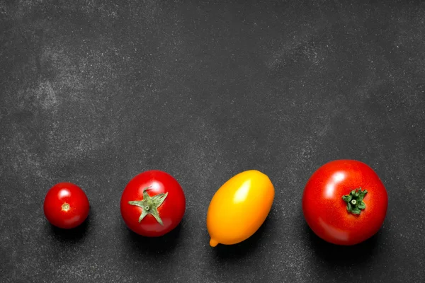 Tomates na superfície preta — Fotografia de Stock