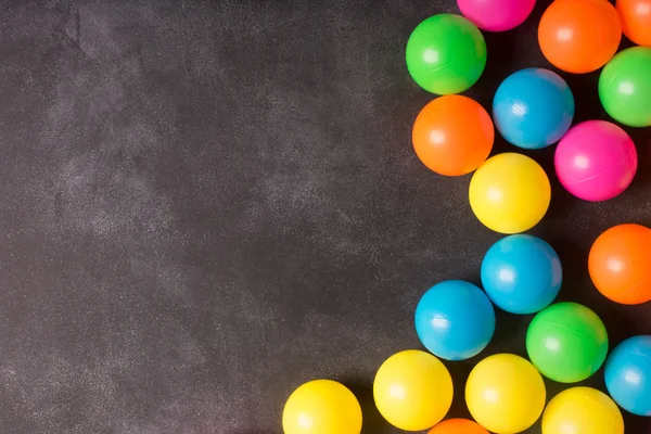 Colorfull plastic balls on the black chalkboard — Stock Photo, Image