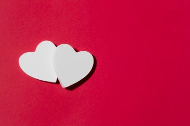 White hearts on a red paper background. Valentine's Day creative concept with copy space