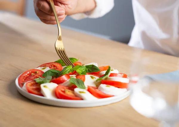 Sałatka Caprese. Człowiek jedzący słynną sałatkę włoską ze świeżymi pomidorami, serem mozzarella i bazylią — Zdjęcie stockowe