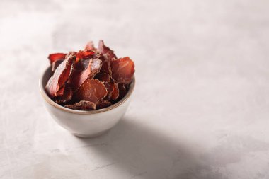 Gri arkaplanda kurutulmuş et ile kase