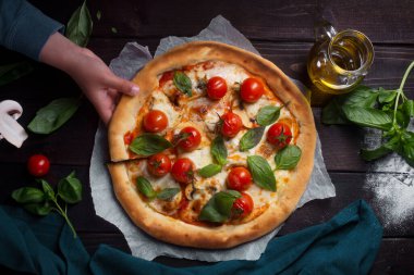 Domatesli pizza, mantar ve fesleğen. Çocuk bir dilim pizza alıyor.