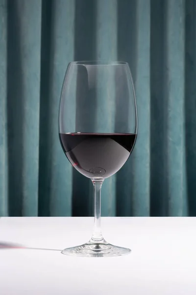 Weinglas Und Auf Einem Weißen Tisch Vor Blauem Vorhang — Stockfoto
