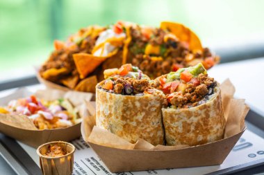 Bir fast food kafede geleneksel Meksika yemekleri. Salsa nachos ve kıymalı burrito ve guacamole.