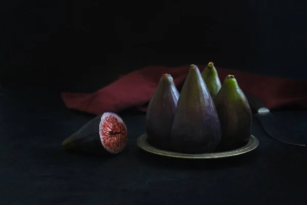 Šťavnaté a zralé plody fíků ve tvaru hrušky leží na talíři a v řezu na tmavém pozadí — Stock fotografie