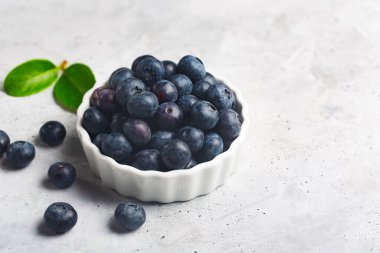 Gri beton arka planda beyaz bir kasede diyet yiyecekler ve bir yaprak için organik böğürtlen. Boşluğu kopyala