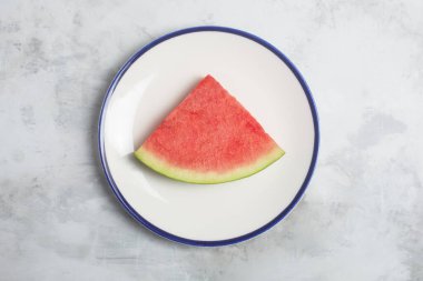Gri arka planda bir karpuz parçası. Tatlı, sulu et, genellikle koyu kırmızıdan pembeye