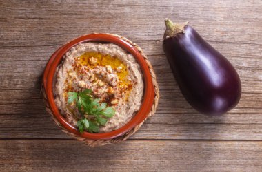 Levantine mutfak aperatifi fırında patlıcan ve susam ezmesi zeytinyağı, baharat, otlar ve ceviz ile ahşap bir arka planda patlıcan. Yukarıdan görüntüle
