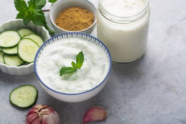 Geleneksel Hint Raita 'sı salatalık, Yunan yoğurdu ve gri arka planda kişniş.